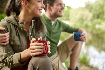 Image showing happy couple with cups drinking in nature