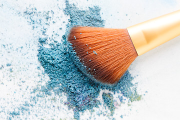 Image showing Blank background with crumbly blue eye shadows and brush