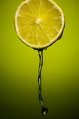 Image showing Lime juice pouring down from half of lime