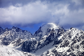 Image showing Snow mountaims in clouds at sunny winter day