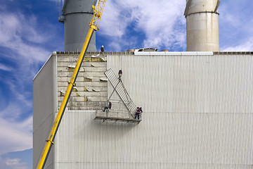 Image showing Workers hanging on the crane and repairing wall paneling on heat