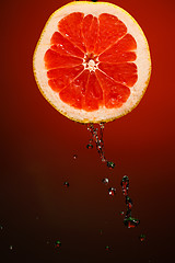 Image showing Juicy grapefruit with stream of fresh water.