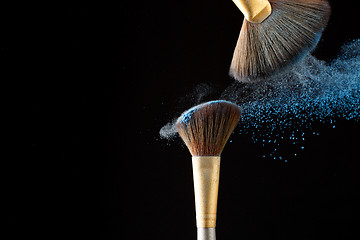 Image showing Beautiful splash after touch of two professional brushes with powder particles on tip