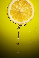 Image showing Splash juice with lemon slice isolated on yellow background