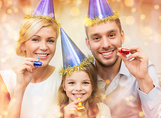 Image showing smiling family in blue hats blowing favor horns