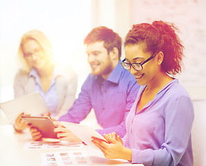 Image showing smiling team with table pc and papers working