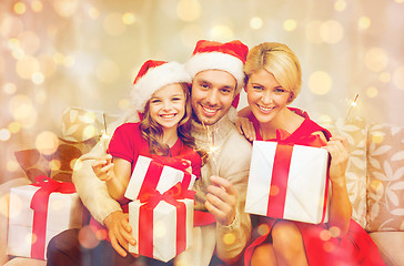 Image showing smiling family holding gift boxes and sparkles