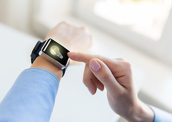 Image showing close up of hands with light bulb on smart watch