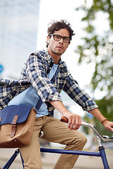 Image showing young hipster man with bag riding fixed gear bike