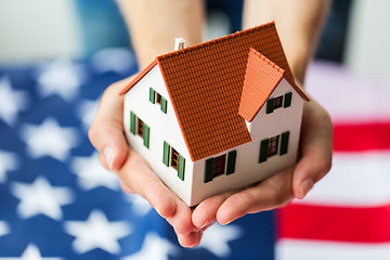 Image showing close up of hands holding house over american flag