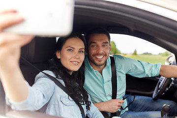 Image showing happy couple in car taking selfie with smartphone