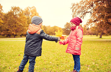 Image showing little boy giving autumn maple leaves to girl