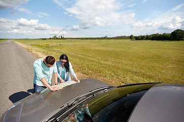 Image showing happy man and woman with road map on car hood