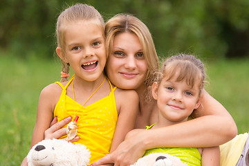 Image showing Young mother hugging her two daughters, five and seven years