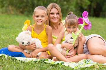 Image showing Young mother sitting on a picnic in a clearing with two daughters