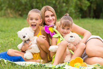 Image showing Mother and two daughters sitting with soft toys on a picnic
