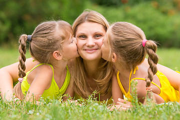 Image showing Two daughters kissing mother lying on the grass on a picnic