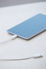 Image showing Digital tablet with USB cable laying on a table