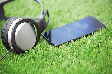 Image showing Headset and smartphone laying on a grass