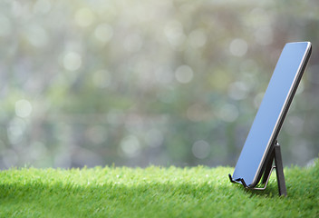 Image showing Digital tablet standing on a grass