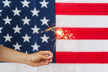 Image showing close up of hand with sparkler over american flag