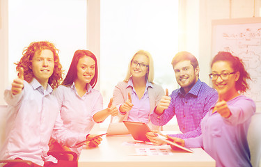 Image showing smiling team with table pc and papers working