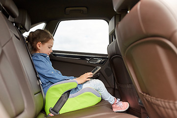 Image showing happy little girl with tablet pc driving in car