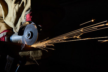 Image showing Worker cutting metal with grinder. Sparks while grinding iron