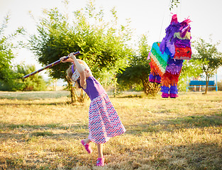 Image showing Young girl at an outdoor party hitting a pinata