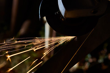 Image showing Worker cutting metal with grinder. Sparks while grinding iron