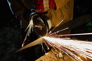 Image showing Worker cutting metal with grinder. Sparks while grinding iron