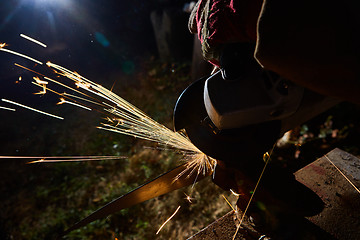 Image showing Worker cutting metal with grinder. Sparks while grinding iron