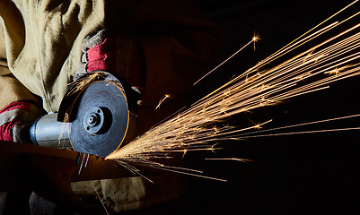 Image showing Worker cutting metal with grinder. Sparks while grinding iron