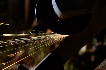 Image showing Worker cutting metal with grinder. Sparks while grinding iron