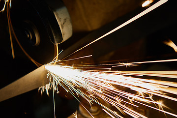 Image showing Worker cutting metal with grinder. Sparks while grinding iron