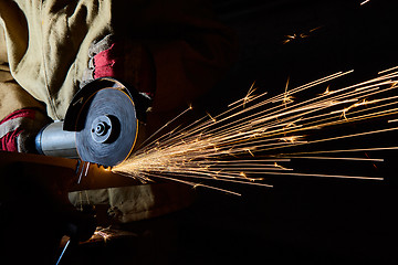 Image showing Worker cutting metal with grinder. Sparks while grinding iron