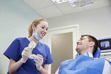 Image showing happy dentist showing jaw layout to male patient