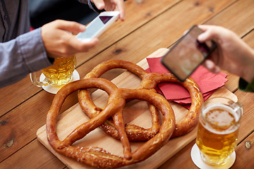 Image showing close up of hands picturing pretzel by smartphone