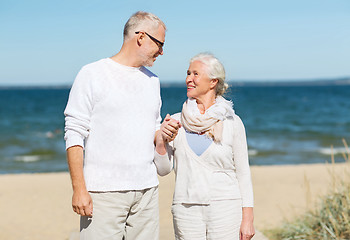 Image showing happy senior couple holding hands on summer beach