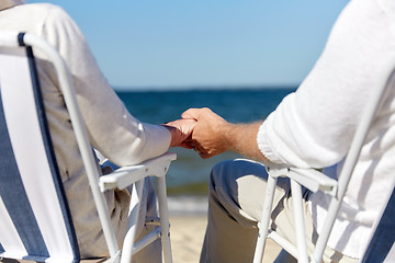 Image showing senior couple sitting on chairs at summer beach