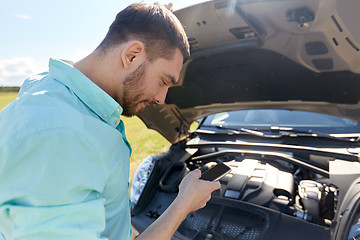 Image showing man with smartphone and broken car at countryside