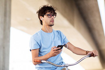 Image showing man with smartphone and earphones on bicycle