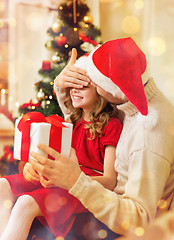 Image showing smiling father surprises daughter with gift box