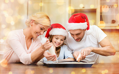 Image showing happy family in santa helper hats making cookies