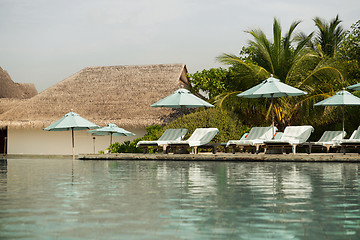 Image showing parasol and sunbeds by sea on maldives beach