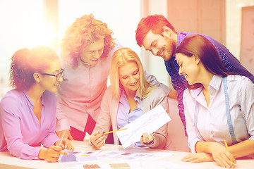 Image showing smiling creative team looking at sketch