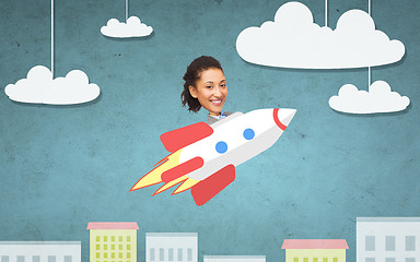 Image showing businesswoman flying on rocket above cartoon city