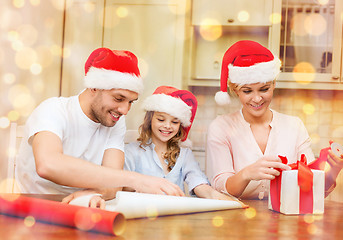 Image showing smiling family in santa helper hats with gift box