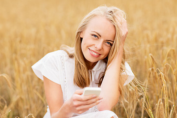 Image showing happy young woman with smartphone on cereal field