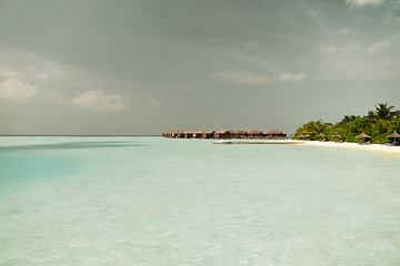 Image showing bungalow huts in sea water on exotic resort beach